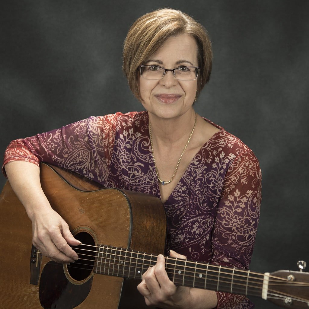 betsy rome photo smiling with a guitar.