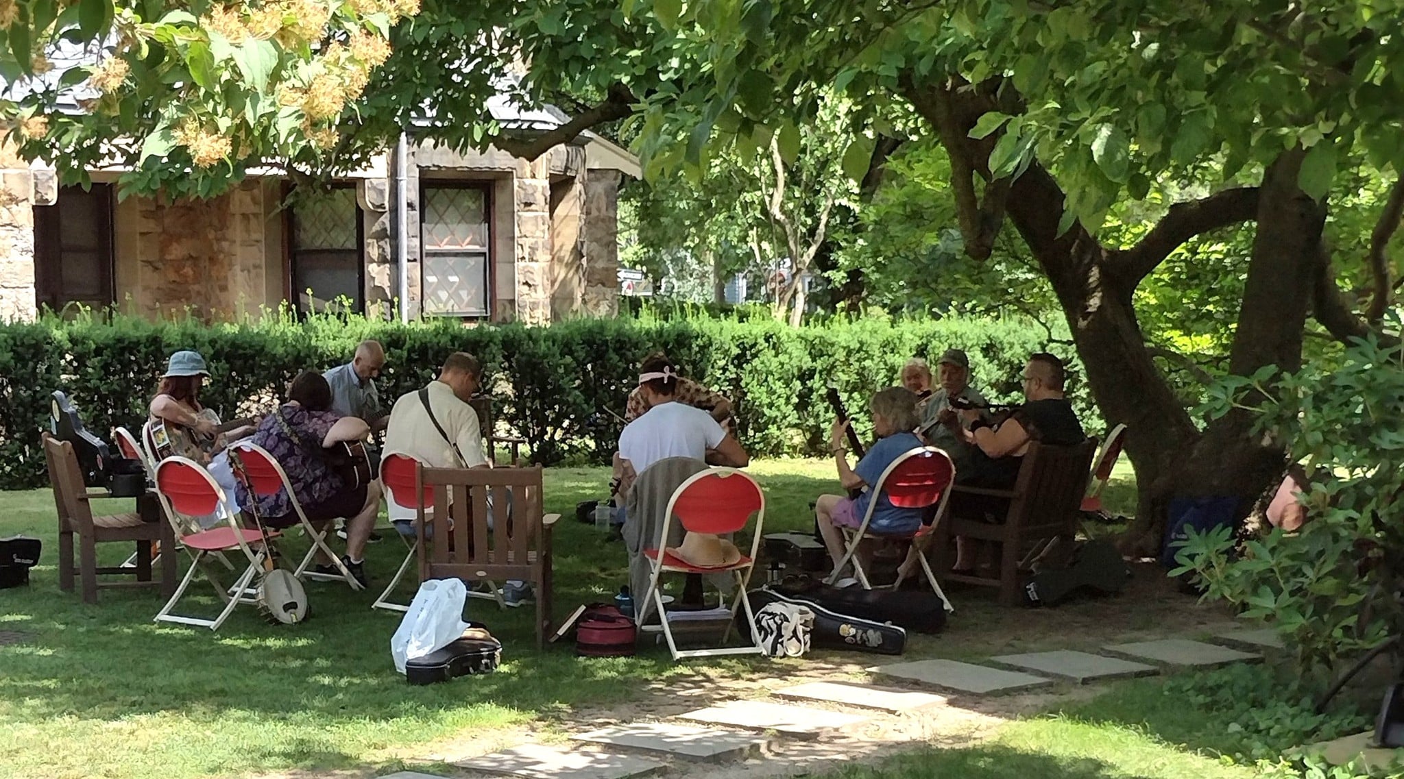 People in a park playing music under shade trees.