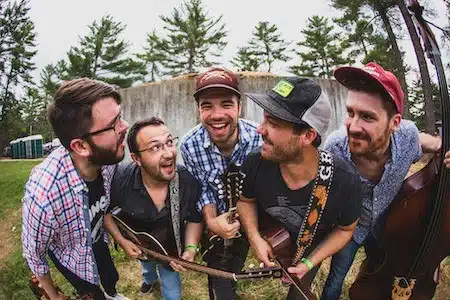 photo of 5 dudes with instruments, smiling