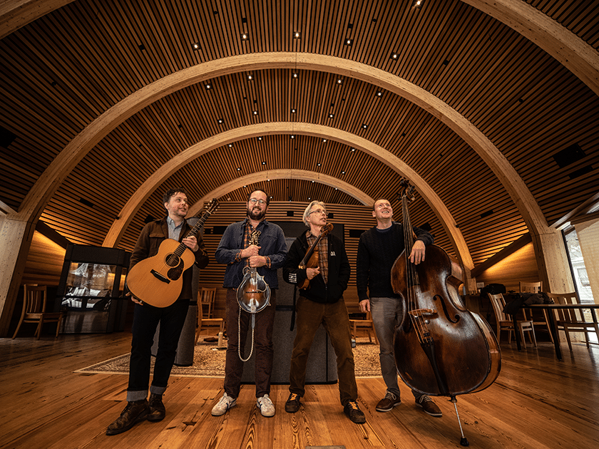 photo of the Mr. Sun band in a concert hall holding a guitar, mandolin, fiddle, and bass