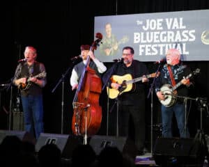 Special Consensus on stage at Joe Val. Mandolin, bass, guitar, and banjo across the stage.